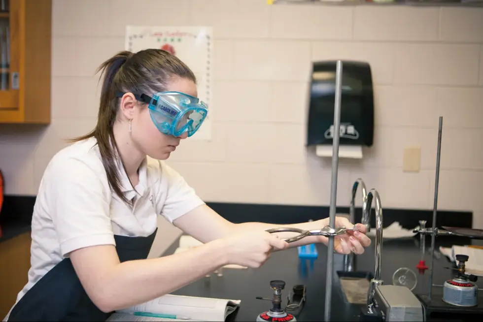 A student in safety goggles working in a science lab