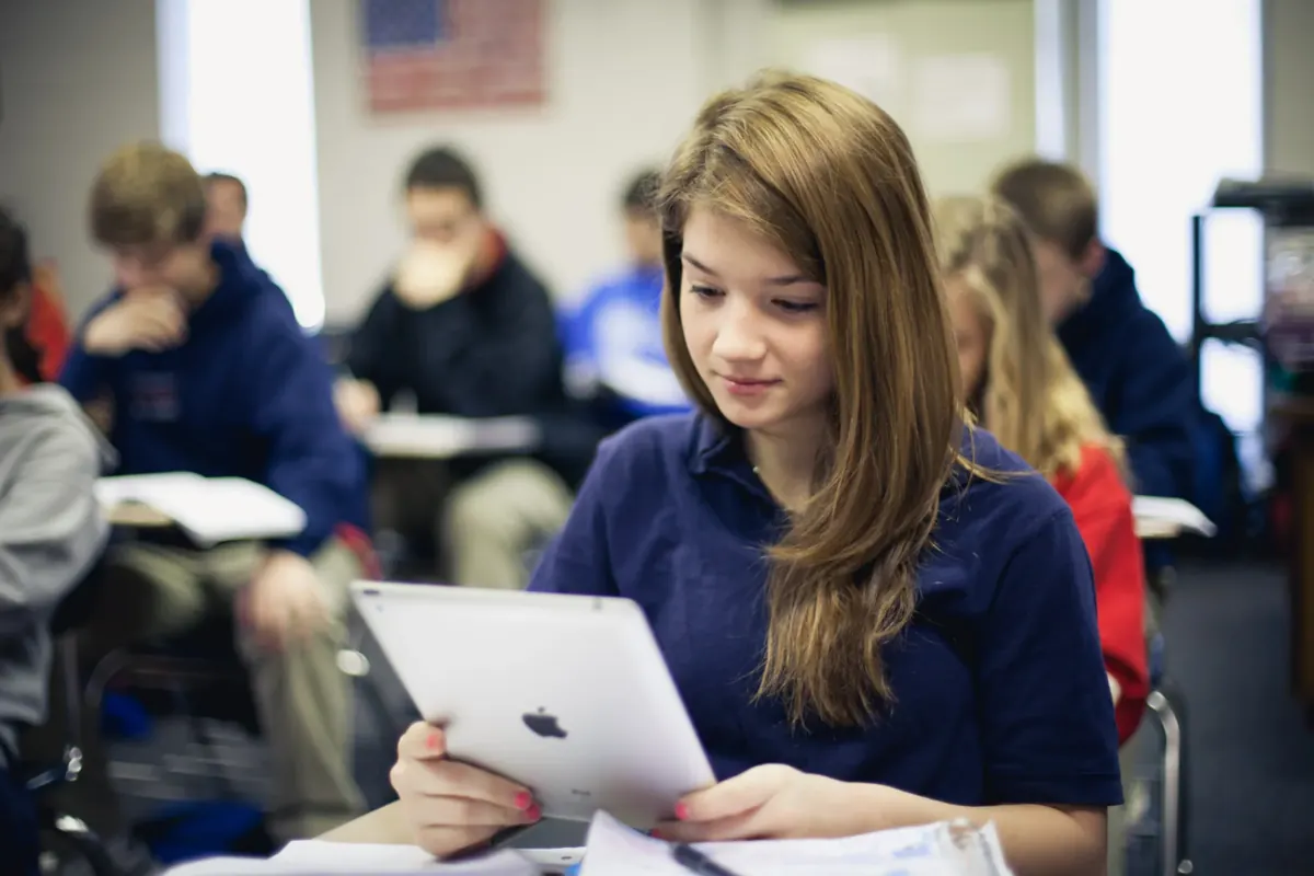 A high school student reading on an iPad during class