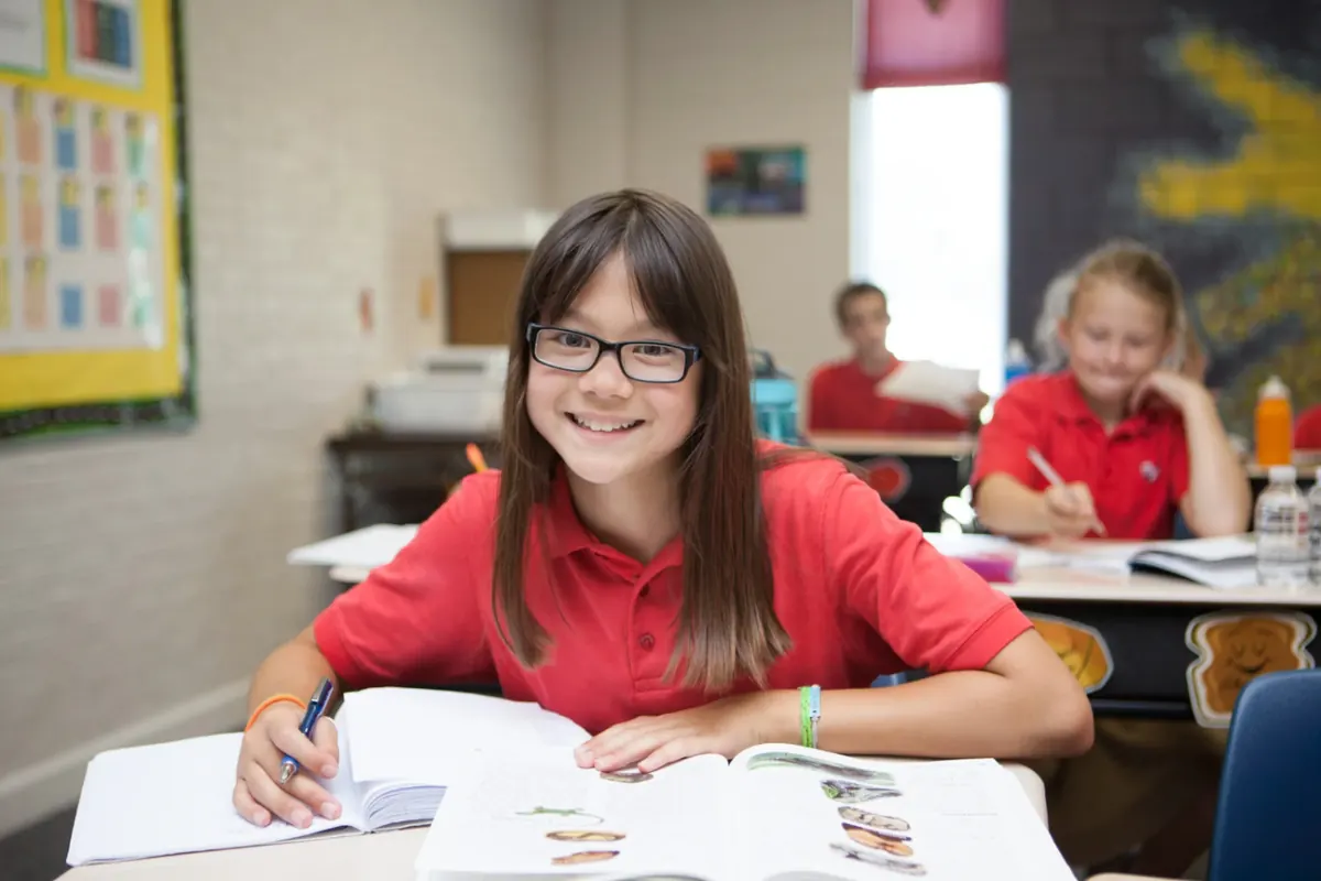 A smiling elementary student reading at her desk