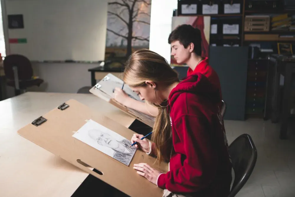 High school students drawing portraits on easels in the art studio