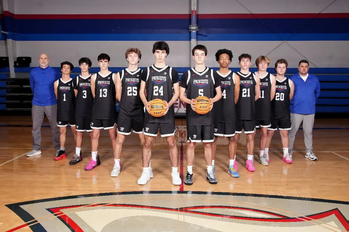 The varsity boys basketball team and coaches on the home court