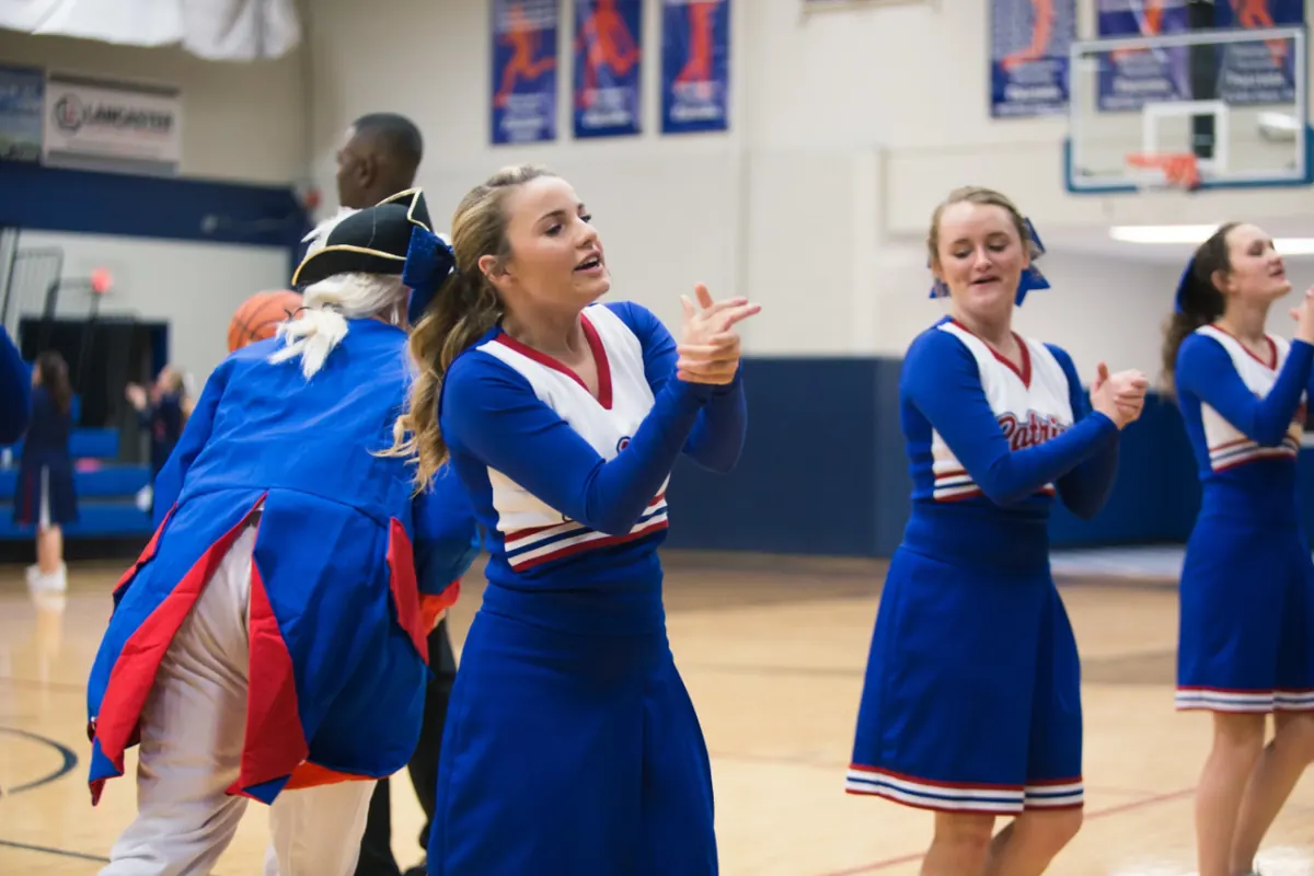 Patriots cheerleaders and the Patriot mascot rallying the crowd at a home basketball game