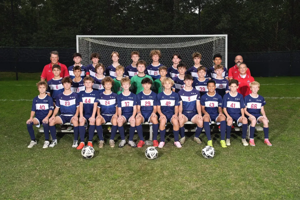 The Patriots boys soccer team and coaches on the field in front of a goal