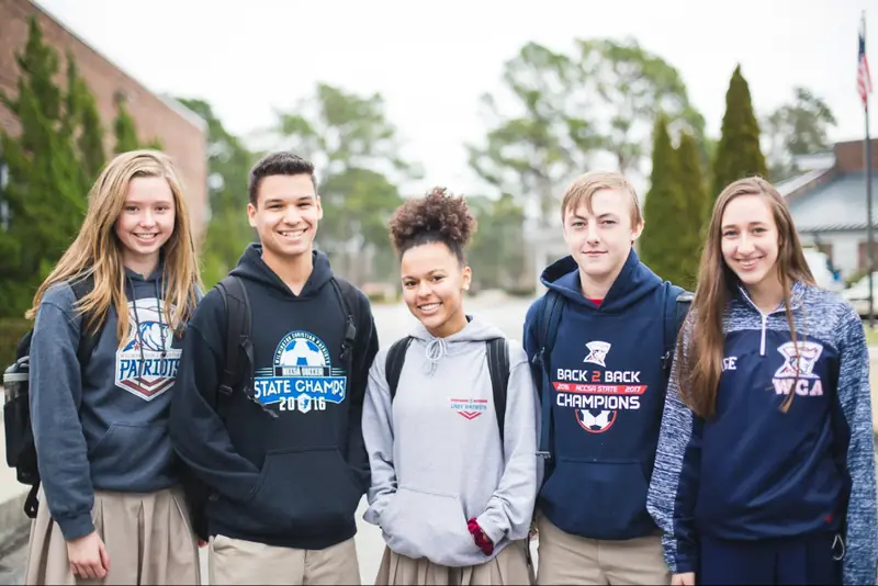 Five high school students smiling outdoors in WCA sweatshirts