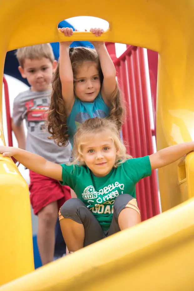Preschoolers playing on a bright playground slide