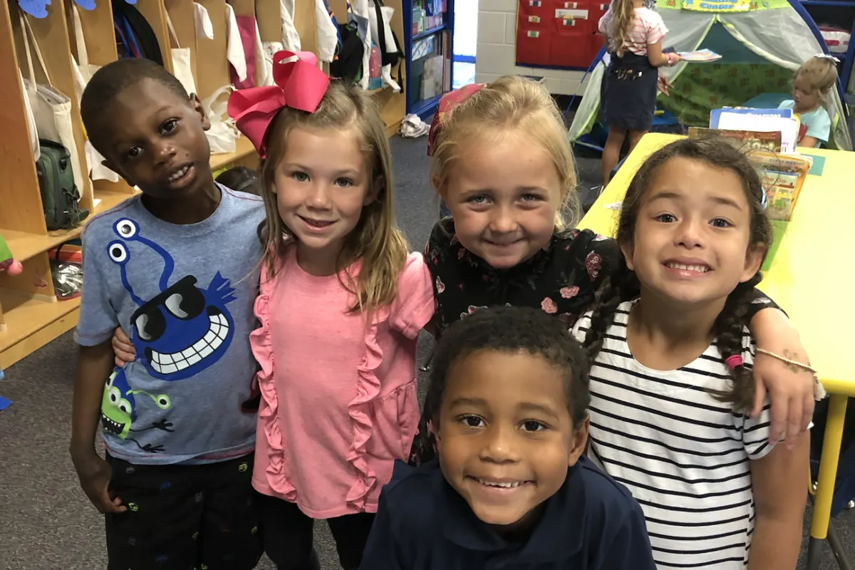 Five smiling kindergarten friends in their classroom