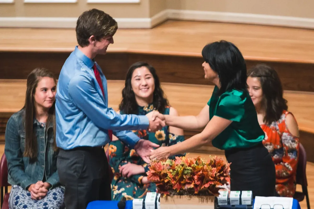 A student shaking hands on stage during an honor society induction