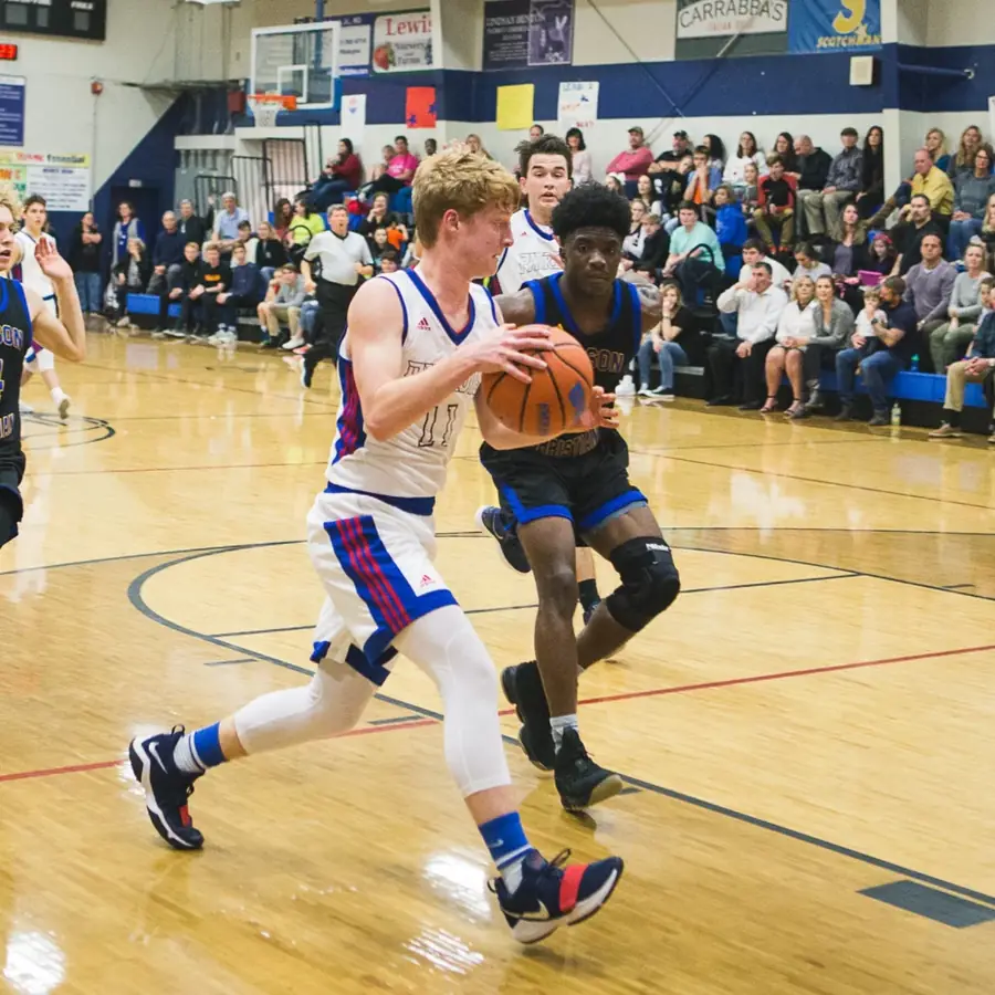 A Patriots basketball player driving to the basket in the gym
