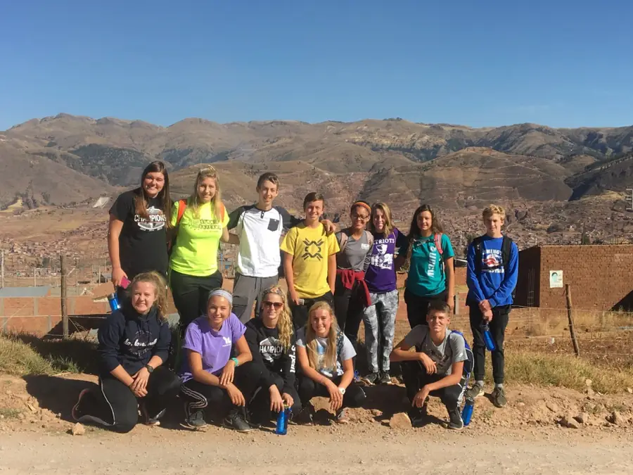A WCA mission team in matching T-shirts posing on a dirt road in front of mountains