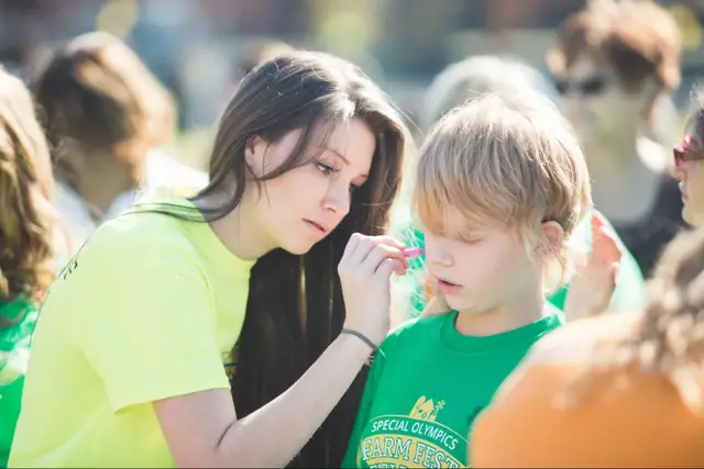 A WCA student face-painting a child at a Special Olympics event