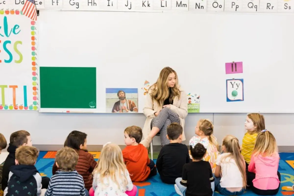 A preschool teacher reading to her class gathered on the carpet